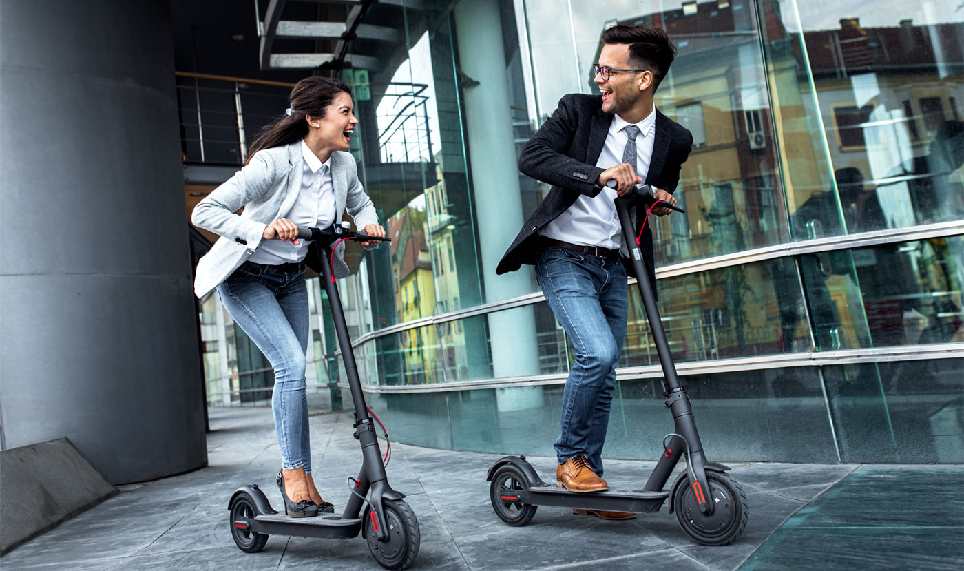 man and woman riding electric scooters